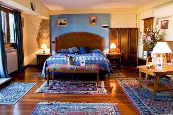 Ett sovrum med en stor säng som har blå sängkläder, träinredning och dekorationer. (AI-genererad text)