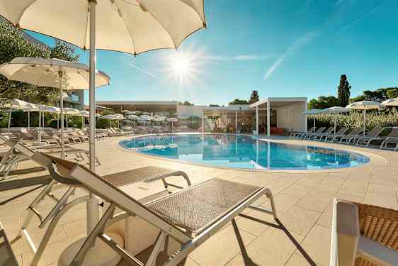 En utomhuspool omgiven av solstolar och parasoller under en klarblå himmel. (AI-genererad text)