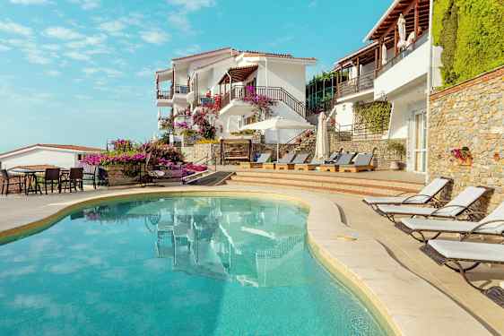 Utomhuspool vid hotell byggt i medelhavsstil med solstolar och blommor. (AI-genererad text)