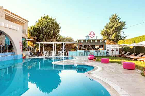 Utomhuspool vid en semesteranläggning med solstolar och en bar i bakgrunden. (AI-genererad text)