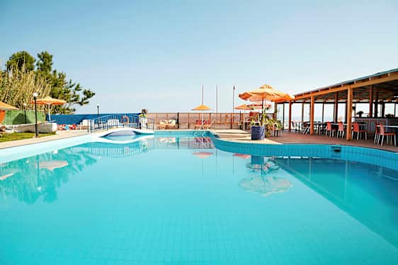 En utomhuspool med parasoll och bord bredvid. (AI-genererad text)