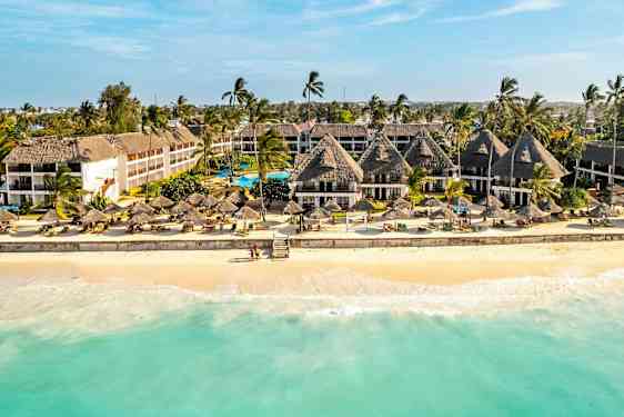 Hotell vid en sandstrand med palmer och parasoller. (AI-genererad text)