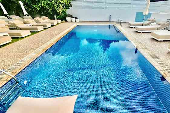 Utomhuspool omgiven av solstolar och parasoller. (AI-genererad text)