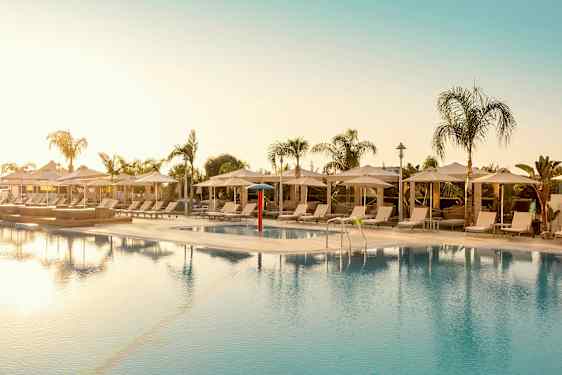 Utomhuspool omgiven av solstolar och parasoller. (AI-genererad text)