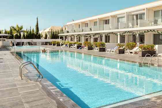 En hotellpool med solstolar och parasoller på sidan. (AI-genererad text)