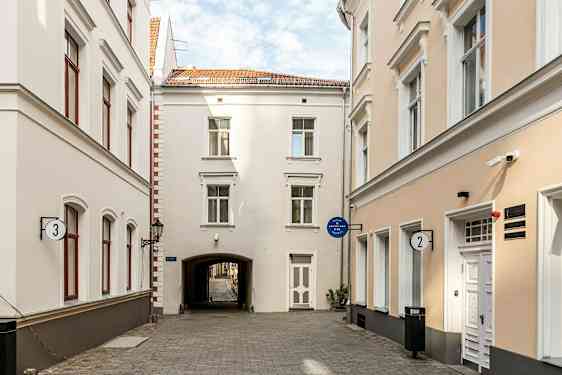 En smal gata omgiven av ljusa byggnader med fönster och dörrar. (AI-genererad text)