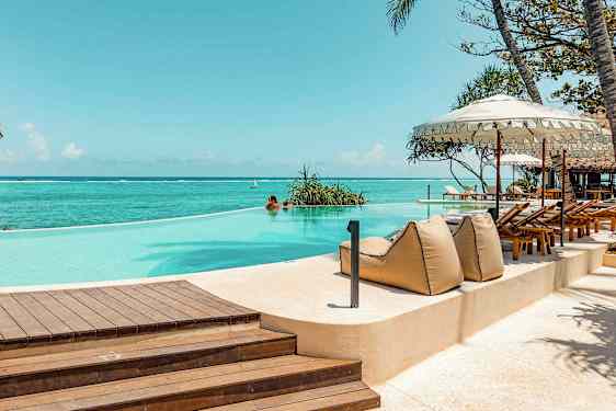 En infinitypool vid havet, omgiven av solstolar och parasoller. (AI-genererad text)