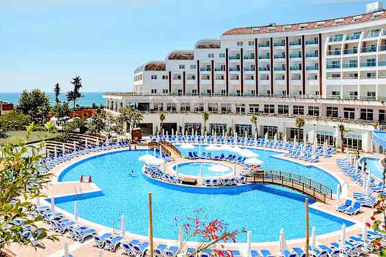 Hotell med stor pool och solstolar vid havet. (AI-genererad text)