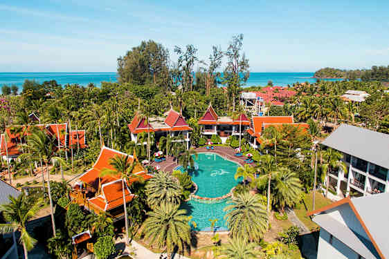 Ett semesterresort med pool, omgiven av tropiska byggnader samt palmer och grönska. (AI-genererad text)