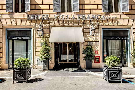 Hotellentré med skylt, fönster och växter i krukor. (AI-genererad text)