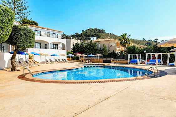 Poolområde med solstolar och parasoller samt omgivande byggnader. (AI-genererad text)