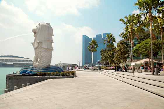 Bild på Merlion-statyn i Singapore med fontän, omgiven av modern arkitektur och palmer. (AI-genererad text)