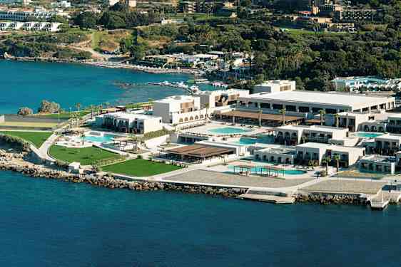 Flygvy över ett hotellkomplex vid kusten, med pooler och grönområden. (AI-genererad text)