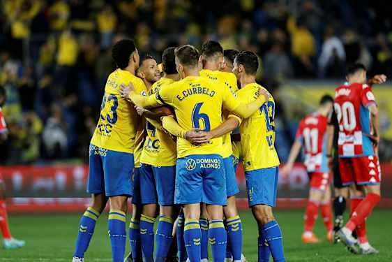 Fotbollsspelare i gula tröjor kramar varandra på planen. (AI-genererad text)