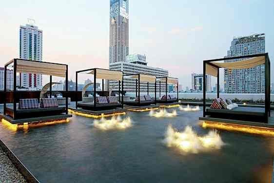 Bild av en modern stadsutsikt med dagbäddar som står ovanpå en grund pool med ljusinstallationer i vattnet. (AI-genererad text)