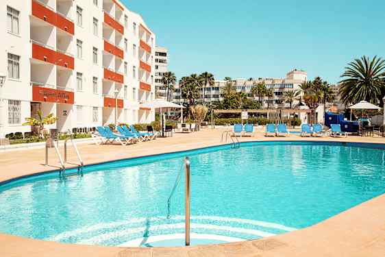 En utomhuspool med solstolar vid ett hotell. (AI-genererad text)