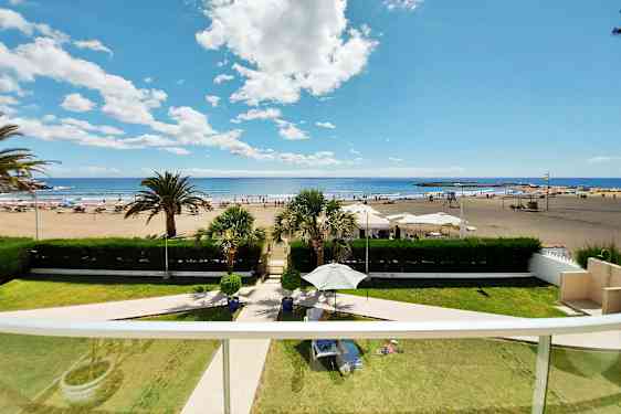 En vy från balkong med utsikt över en sandstrand, solstolar och parasoller samt havet och himlen. (AI-genererad text)