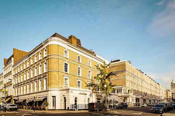 En gata med en rad klassiska byggnader och parkerade bilar. (AI-genererad text)