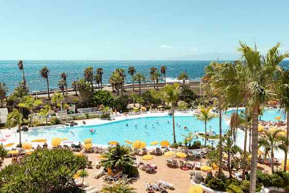 Poolområde med solstolar, parasoller och människor, med havet i bakgrunden. (AI-genererad text)