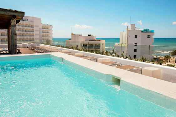 En pool med utsiktsplats mot en strand med flera byggnader i bakgrunden. (AI-genererad text)