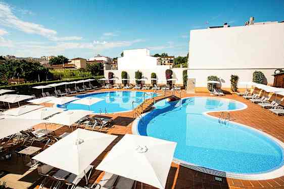 En utomhuspool omgiven av solstolar och parasoller. (AI-genererad text)