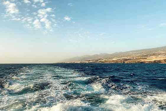 Havslandskap med vågor och kustlinje i bakgrunden. (AI-genererad text)