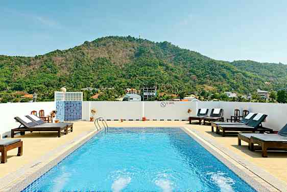 Utomhuspool med solstolar och berg i bakgrunden. (AI-genererad text)