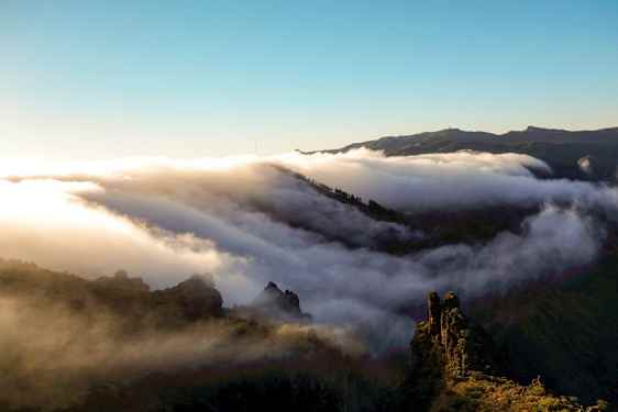 Moln sveper över en bergskedja vid soluppgång eller solnedgång. (AI-genererad text)