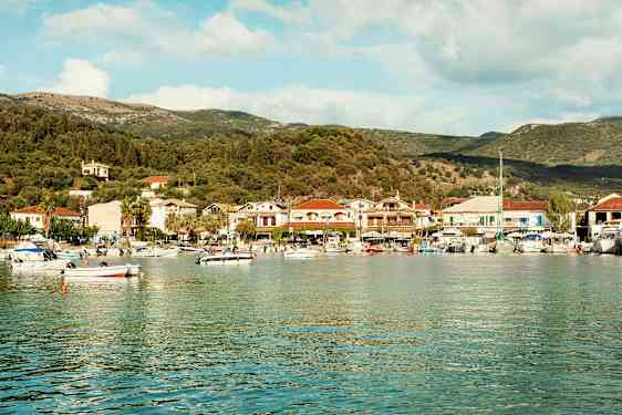 En havsvik med småbåtar och en kuststad fylld med hus och träd i bakgrunden. (AI-genererad text)