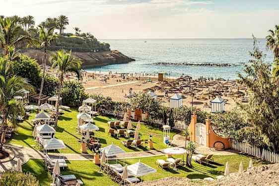 Vy över strand med parasoller och solstolar vid havet. (AI-genererad text)