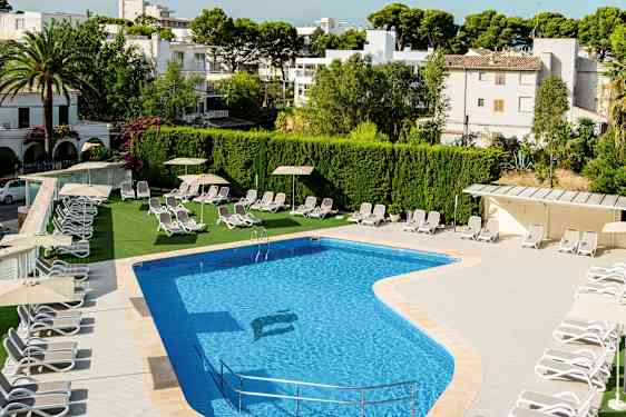 Utomhuspool med solstolar och parasoller vid sidan, omgiven av grönska och byggnader. (AI-genererad text)