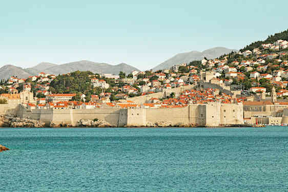 Stenstadsmurar och röda tak vid havskust. (AI-genererad text)