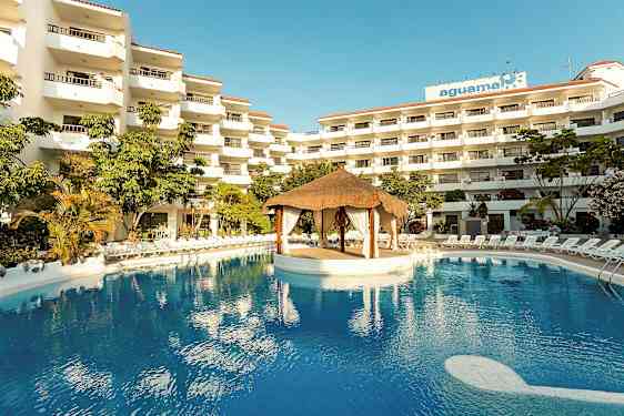 Hotellkomplex med flera våningar, en stor pool och en takhyddestruktur i mitten av poolen. (AI-genererad text)