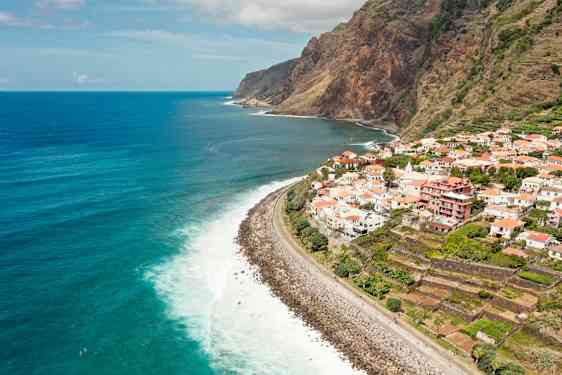 Vy över en kustlinje med en by på klippan och havet i bakgrunden. (AI-genererad text)