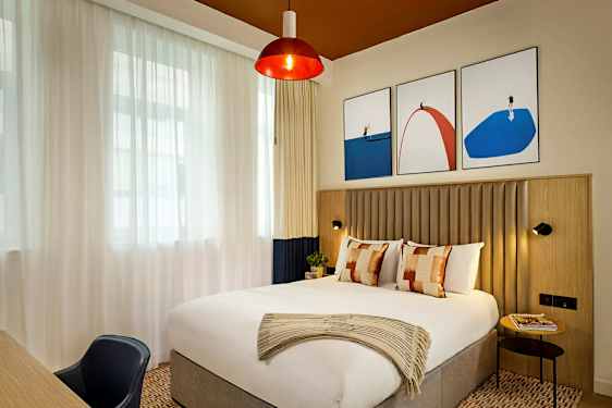 Ett stilfullt hotellrum med en stor säng och moderna konstverk på väggen. (AI-genererad text)