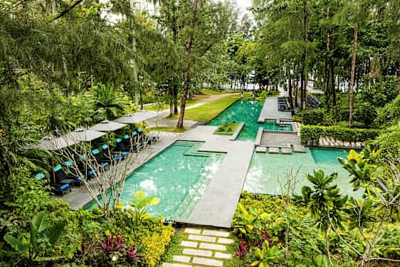 En tropisk utomhuspool med solstolar och gröna omgivningar. (AI-genererad text)