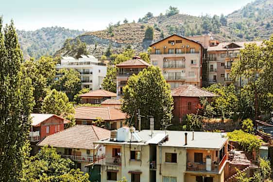 En samling bostadshus bland träd vid en sluttning. (AI-genererad text)