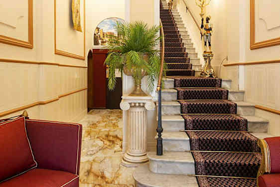 Elegant foajé med röda möbler och en trappa med mönstrad matta. (AI-genererad text)