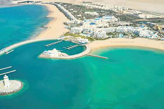 Flygfoto av en kustlinje med en nybyggd marina, hotellkomplex och sandstränder. (AI-genererad text)