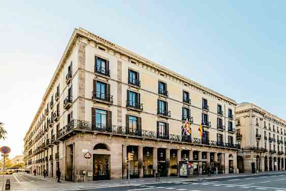 En gatuhörn med en byggnad i klassisk stil, som har flera våningar, valv och dekorerade balkonger. (AI-genererad text)