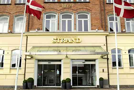 Hotellfasad med skylt där det står 'Copenhagen Strand'. Danska flaggor syns vid ingången. (AI-genererad text)