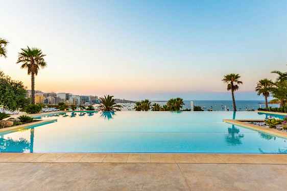 Infinitypool med utsikt över havet, omgiven av palmträd och grönska. (AI-genererad text)