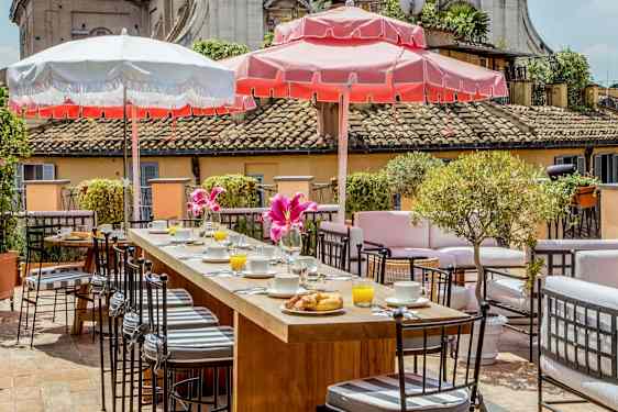 En terrass med sittgrupper, frukostdukning och parasoller i soligt väder. (AI-genererad text)