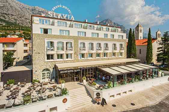 Foto av Grand Hotel Slavia med utomhusterrass och glasad restaurangdel. (AI-genererad text)