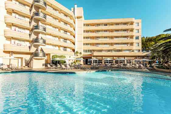 Hotellbyggnad vid en pool med solstolar och parasoller. (AI-genererad text)