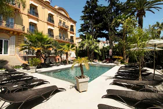 En utomhuspool vid ett hotell omgivet av palmer och solstolar. (AI-genererad text)