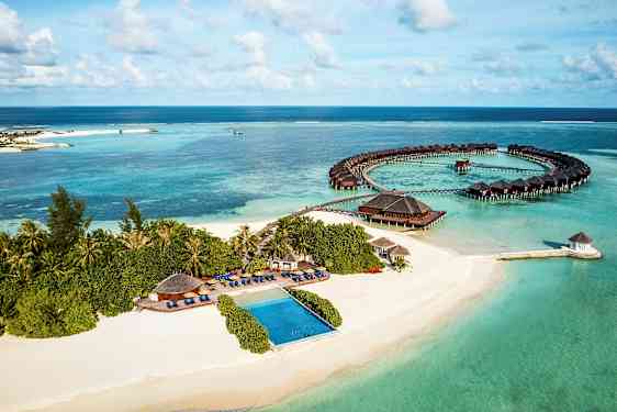 Luftvy av en tropisk kust med sandstrand, hav och övervattensbungalower. (AI-genererad text)