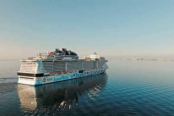 Ett kryssningsfartyg på havet med en stad i bakgrunden. (AI-genererad text)