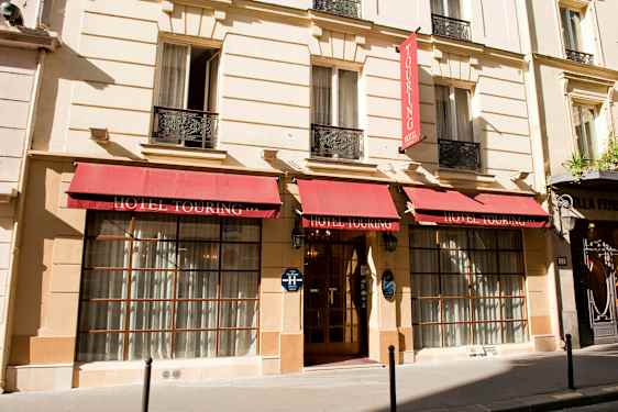 Fasaden på Hotel Touring med röda markiser och ingång med glasdörrar. (AI-genererad text)