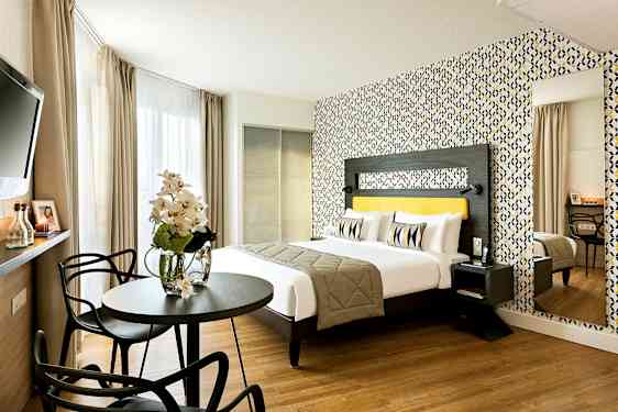 Ett modernt hotellrum med en dubbelsäng, färgglad tapet, och sittgrupp. (AI-genererad text)